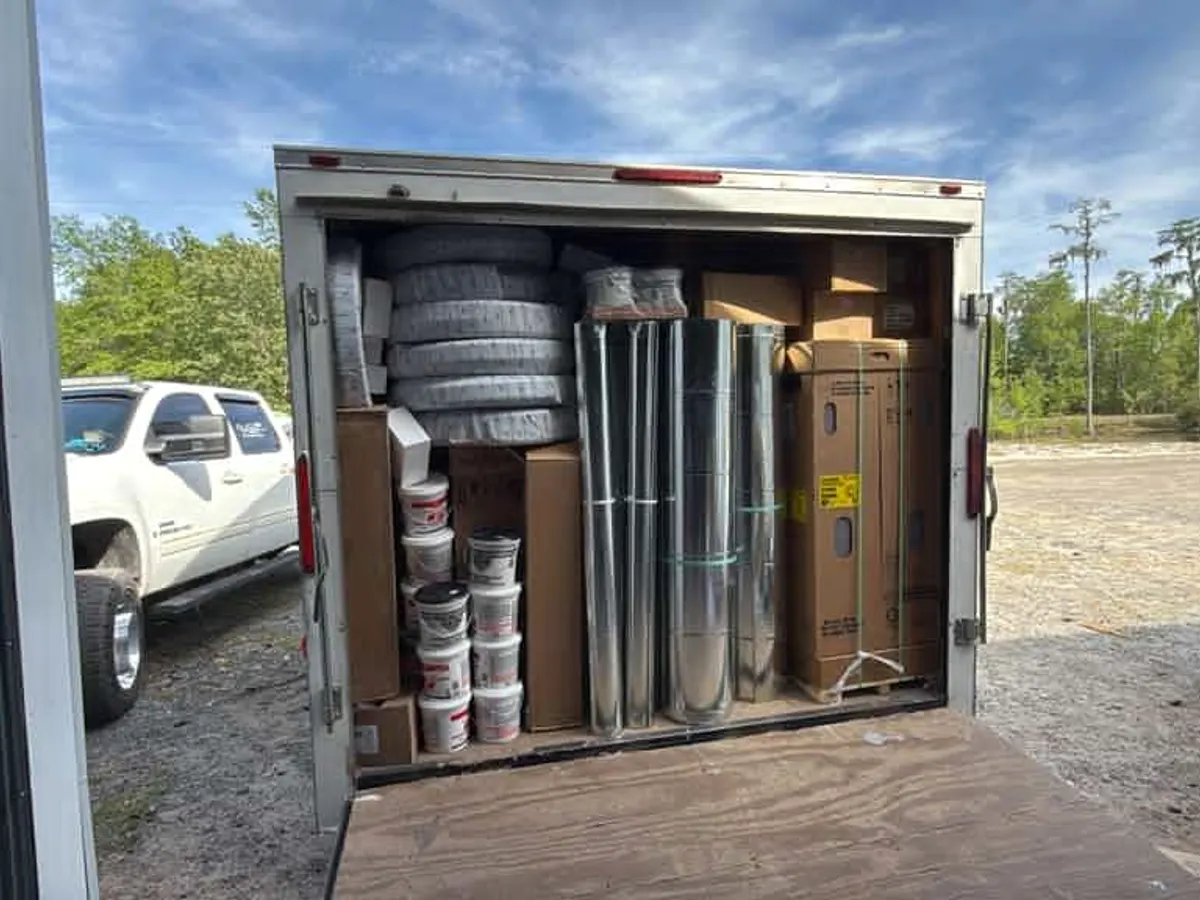 Ventura trailer loaded with duct coils, sheet metal and supplies next to the work truck