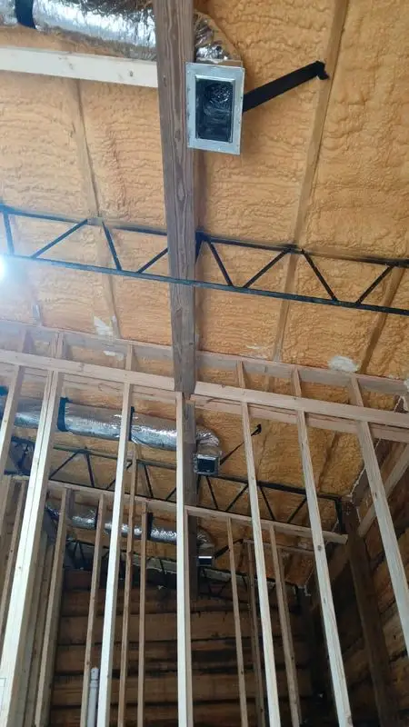Duct runs routed through a spray foam attic under construction